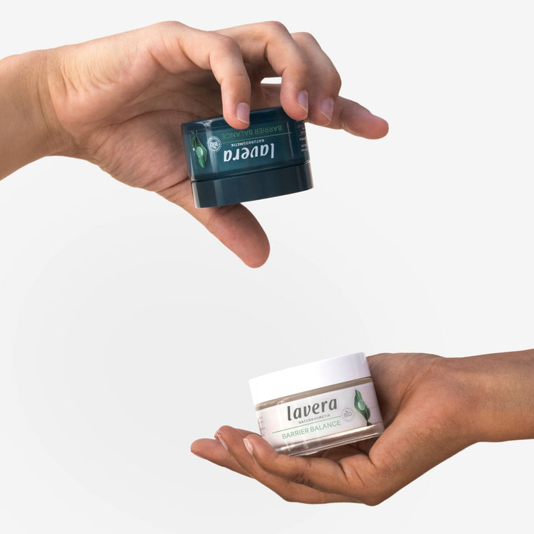 lavera Barrier Balance fragrance-free natural skincare jars held by two people against a plain white background.