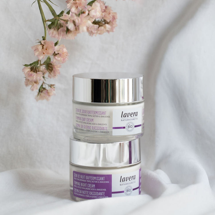 Two stacked jars of Lavera Firming skincare: the Firming Day Cream on top and the Firming Night Cream on the bottom, both featuring Triple-Effect Hyaluronic Acid and Bakuchiol.