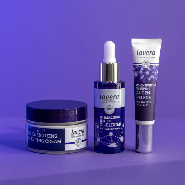 A trio of Lavera Re-Energizing Sleeping skincare products in blue packaging, including a jar of sleeping cream, a bottle of oil elixir with a dropper, and a tube of eye cream.