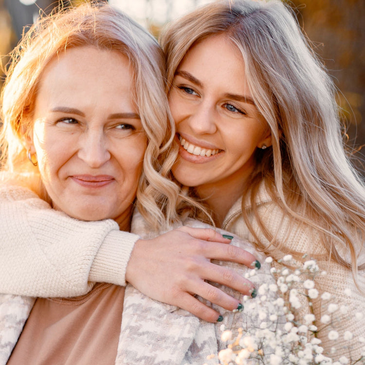 A heartwarming close-up of a smiling young woman embracing her mother outdoors during the golden hour, symbolising Mother's Day and natural beauty.