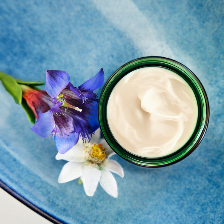 An overhead shot of an open jar of Weleda Contouring Face Cream, showing its rich, white texture.