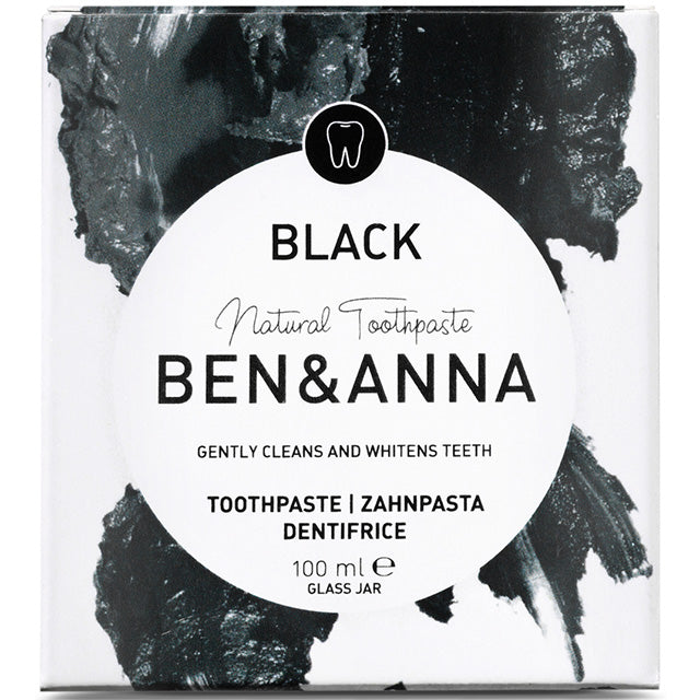 Ben and Anna Black Natural Toothpaste in a glass jar with a spatula in a black and white cardboard box. 