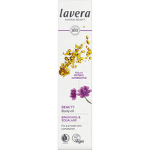 Lavera Beauty Body Oil is in a white box with gold oil drops and a purple flower on a white background