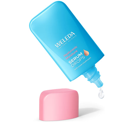 Weleda Hyaluronic Moisture Serum Booster Drops in an open blue bottle showing a drop of serum next to a pink lid. 
