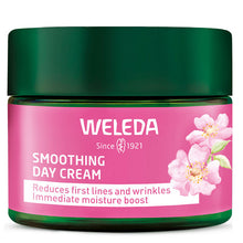Weleda smoothing day cream is in a green jar with pink label with pink flowers and green lid on a white background