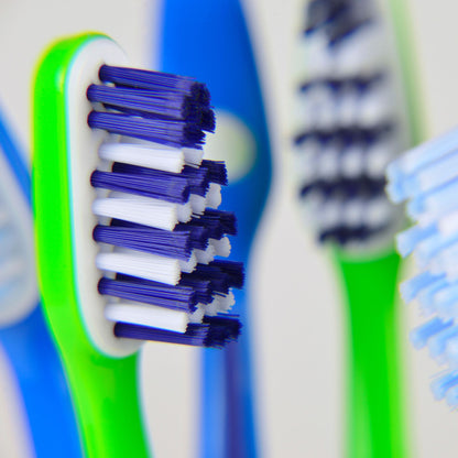 Close-up of a green and blue yaweco bio-based toothbrush with white bristles.