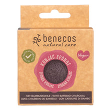 Benecos Natural Care Konjac Sponge in its original kraft paper packaging, showing the dark brown sponge through a circular window and highlighting its vegan and dermalogically tested status.