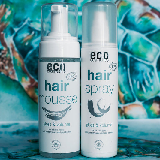 Two eco-friendly hair care products, hair mousse and hair spray, on a colorful background.