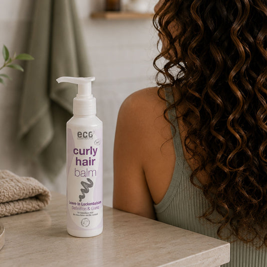 Eco Cosmetics curly hair balm bottle on a bathroom table with curly hair woman