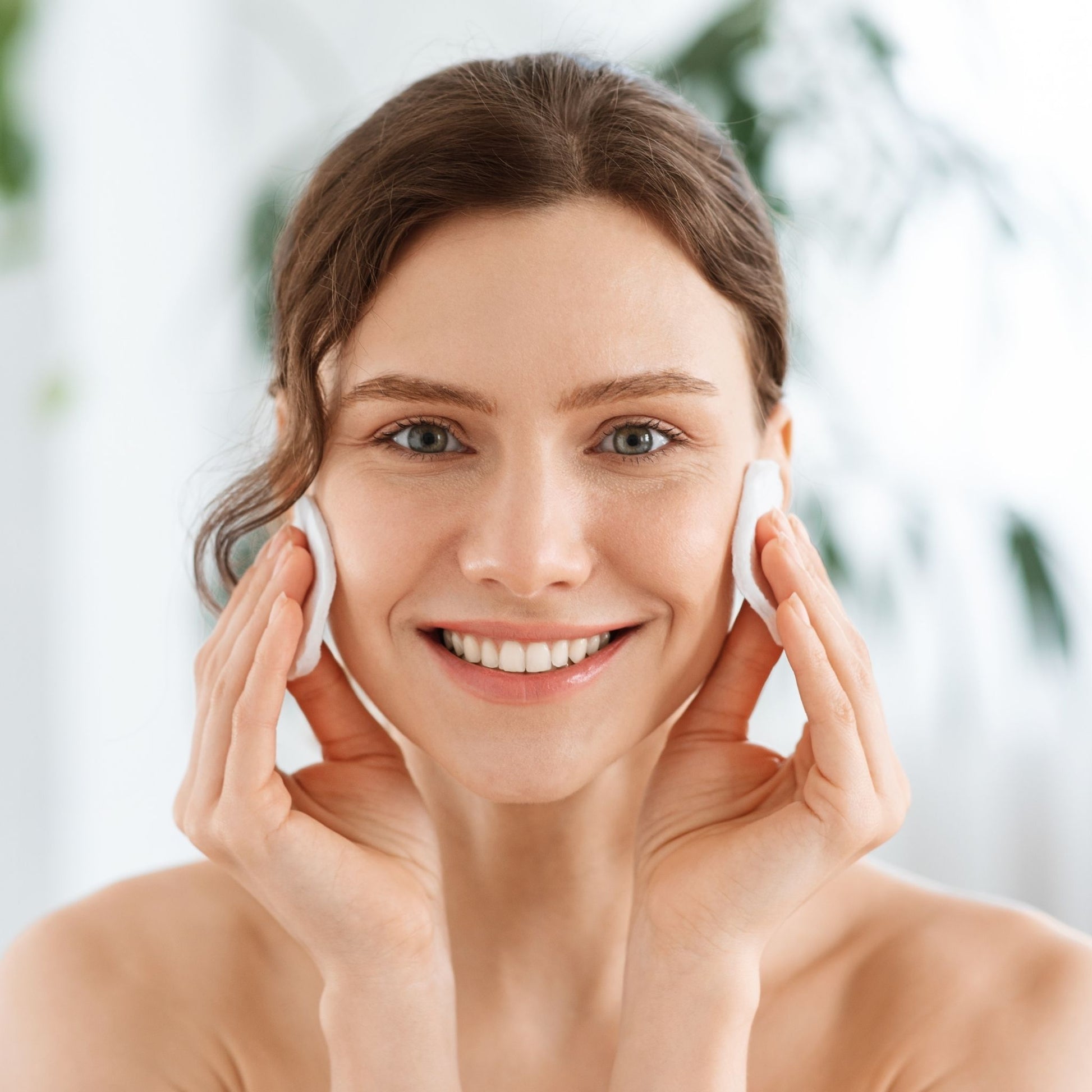 woman cleansing her face with cotton pad with natural light background