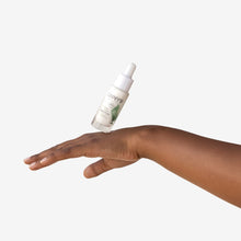 Lavera Barrier balance eye cream in clear glass dropper bottle with a white dropper cap on a back of hand on a white background.