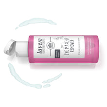 A pink bottle of Lavera Organic Soft Eye Make-Up Remover with a white cap, shown on a white background with decorative light blue makeup smears.