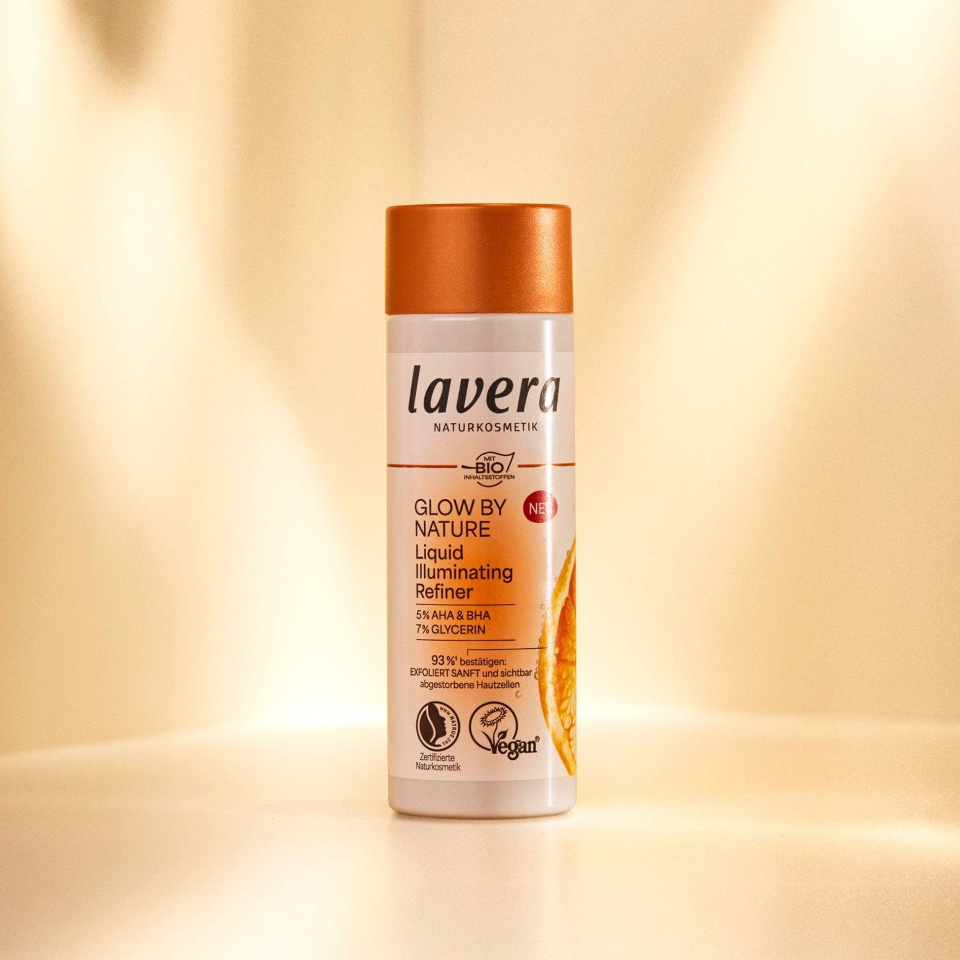 Lavera Glow By Nature Liquid Illuminating  Refiner bottle with a orange lid, on a orange background.