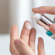 A close-up of a person applying a glossy, translucent lavera hydro refresh serum from a pump bottle onto their finger.