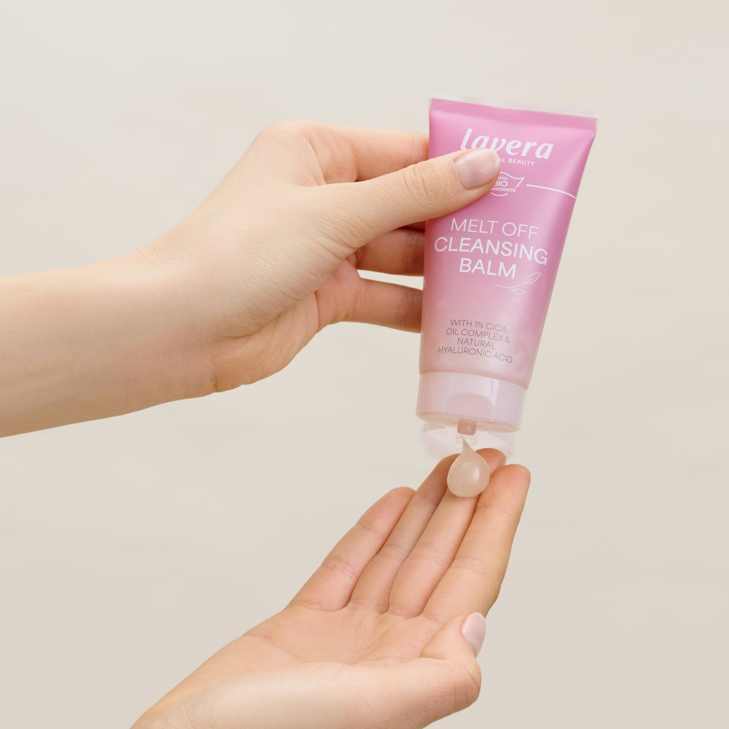 A hand holding a tub of Lavera Melt Off Cleansing Balm