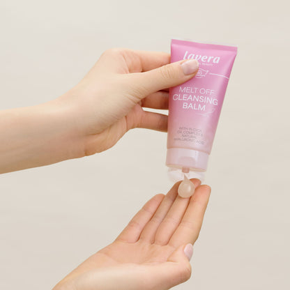 A hand holding a tub of Lavera Melt Off Cleansing Balm