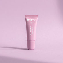Lavera Plumping Lip Balm in a pink tube, presented on a pink background.