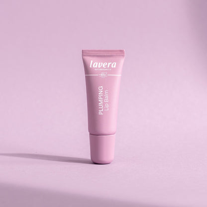 Lavera Plumping Lip Balm in a pink tube, presented on a pink background.