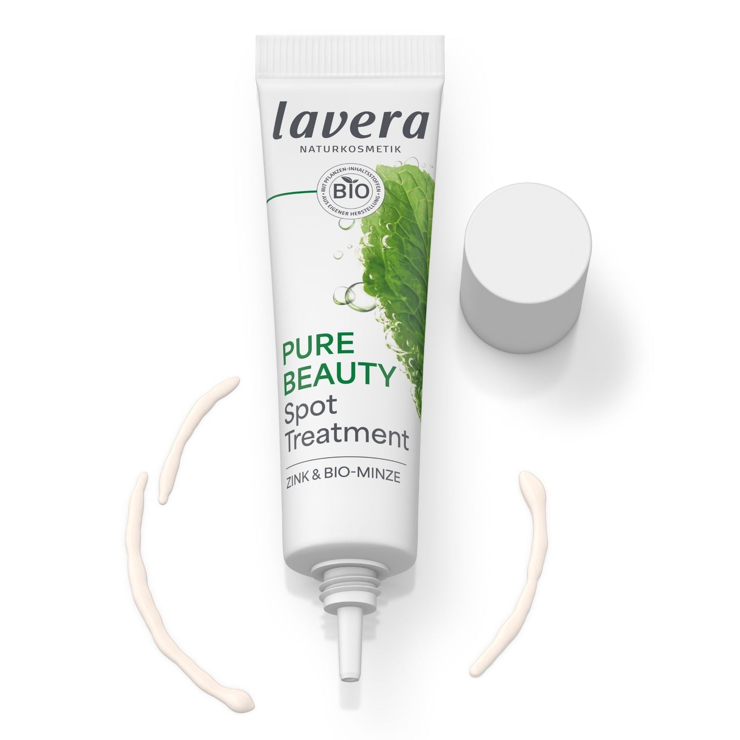 A white tube of lavera Pure Beauty Spot Treatment with green mint graphics, shown with its cap off and two curved smears of the light beige treatment cream on a white background.