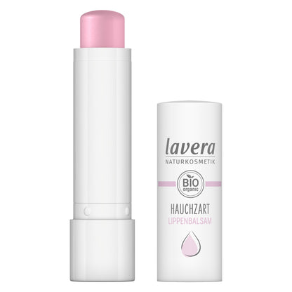 Lavera Natural lip balm shown with the cap removed, revealing a pale pink balm stick, alongside its white cylindrical packaging container on a plain white background.