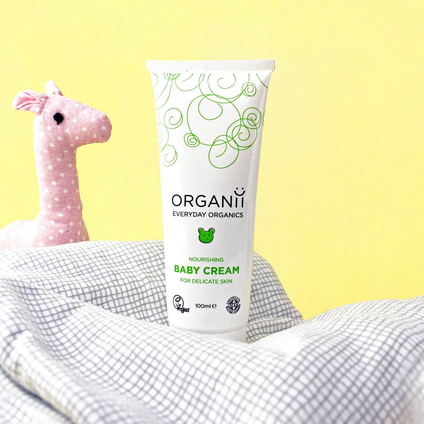 Organii Nourishing Baby Cream For Delicate Skin Tube with baby toy on yellow background