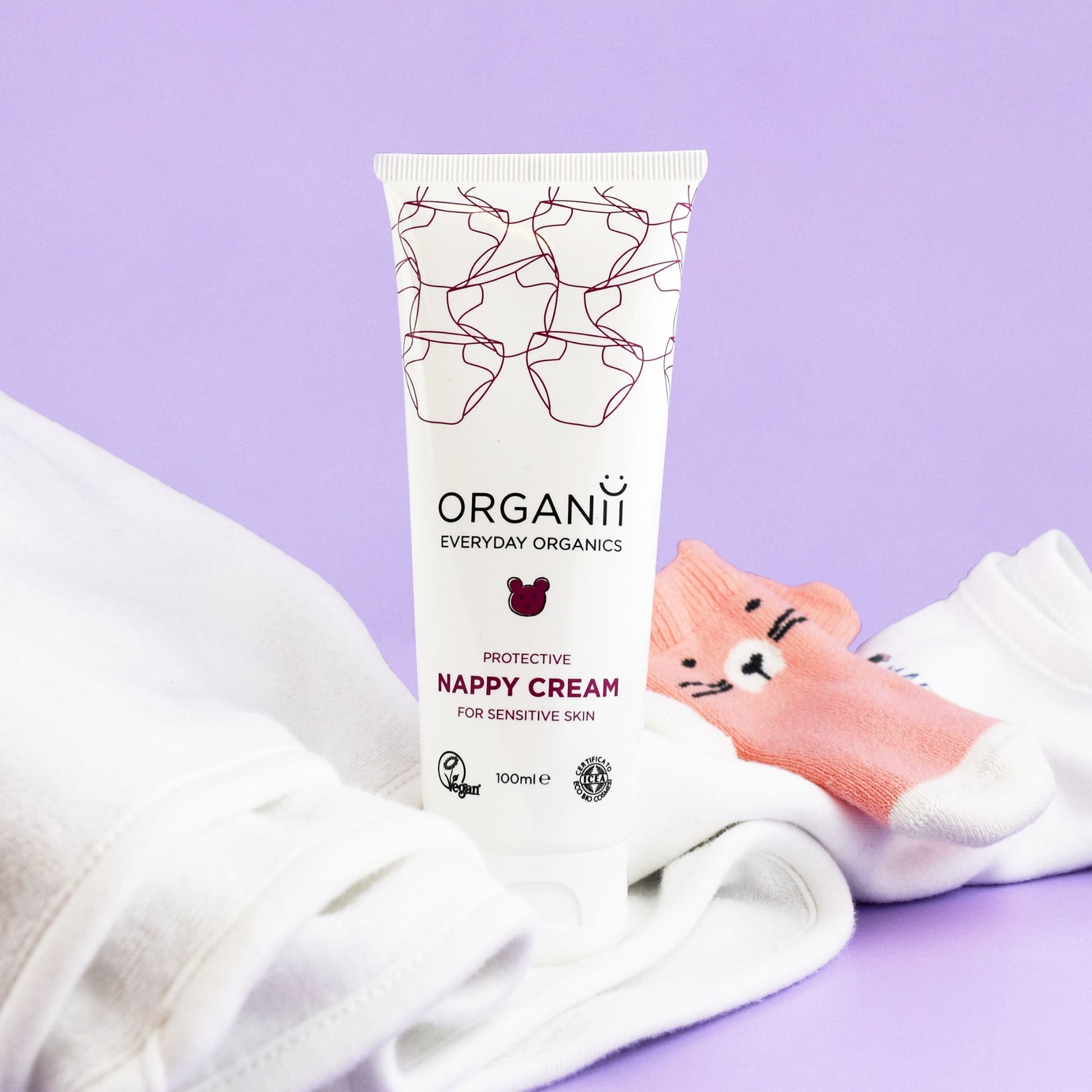 Organii Protective Nappy Cream for Sensitive Skin tube with baby sock on purple background