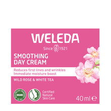 Weleda Smoothing Day Cream packaging box, featuring a pink background with white text, pink rose illustrations, and certification logos for organic and natural skin care. The box is centered on a plain white background.