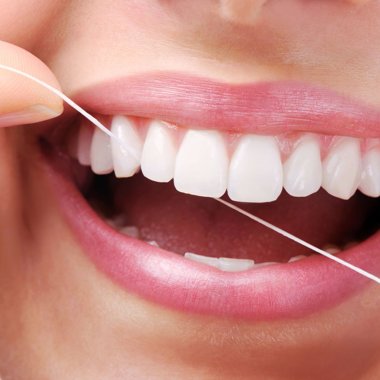 Close-up of a person using dental floss to clean their teeth.