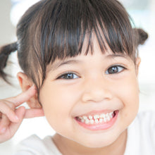 Young girl with pigtails smiling and holding her hand to her ear.